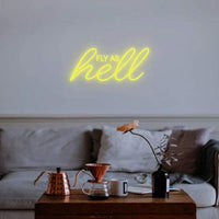 Fly as hell neon sign glowing in yellow on living room wall above couch