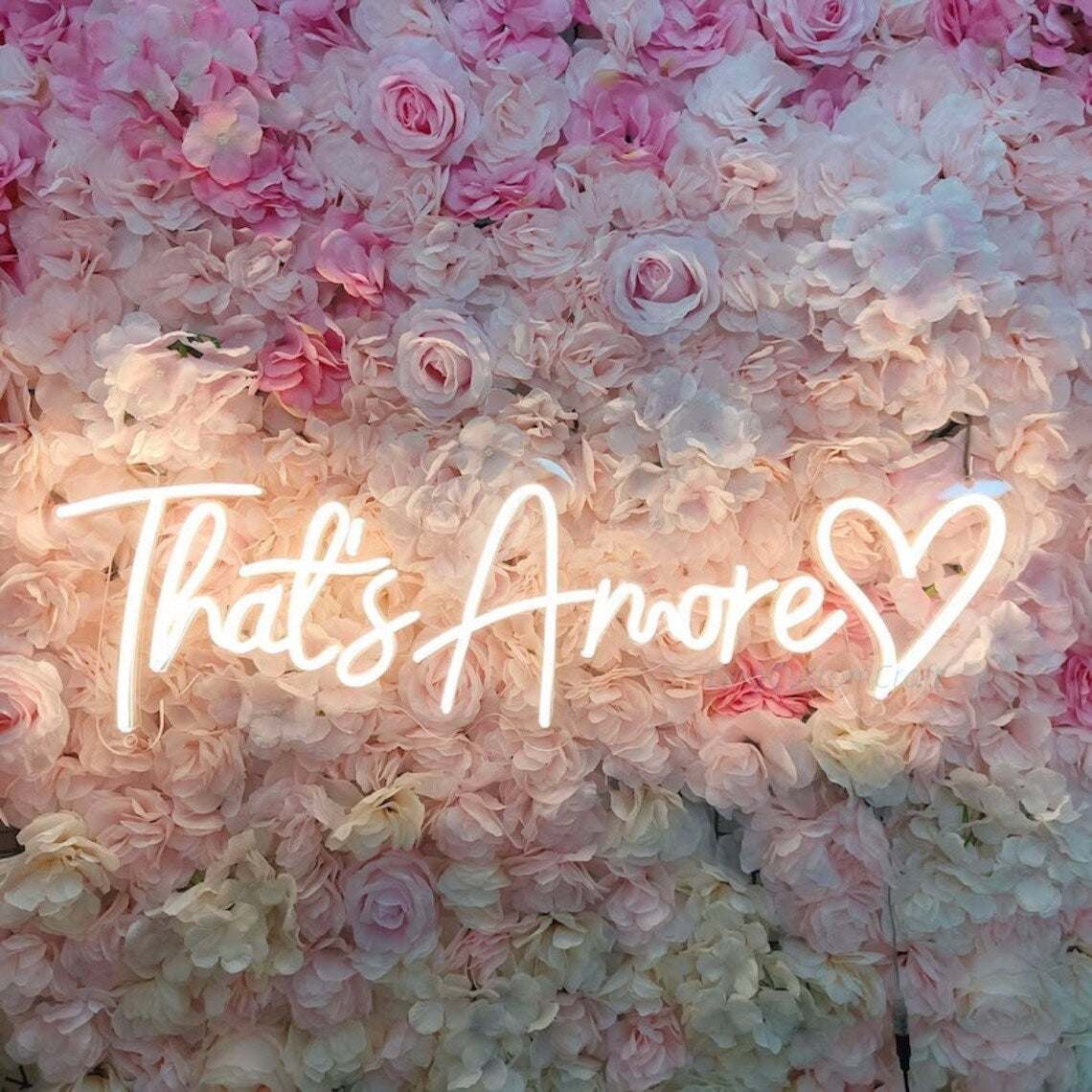 that's amore cuore neon light sign on pink floral wall